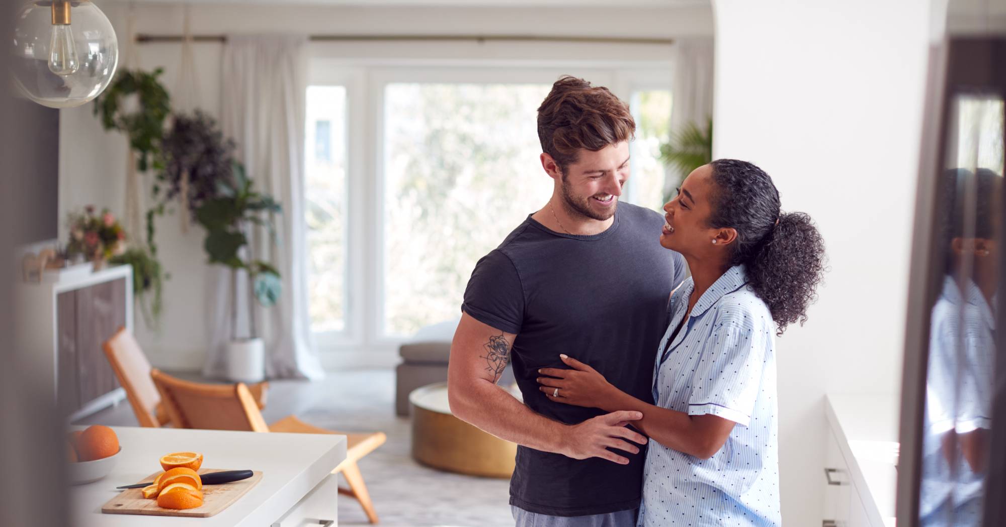 loving-couple-wearing-pyjamas-hugging-in-kitchen